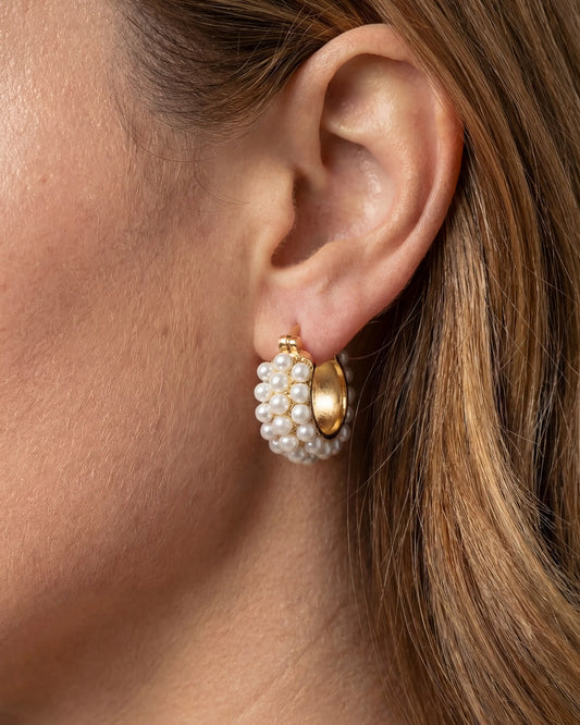 Close-up of an ear wearing a gold and pearl earring.