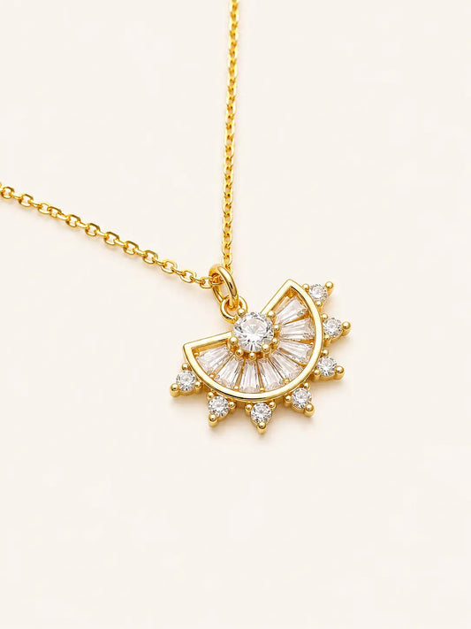 Gold necklace with a sun-shaped pendant on a light beige background