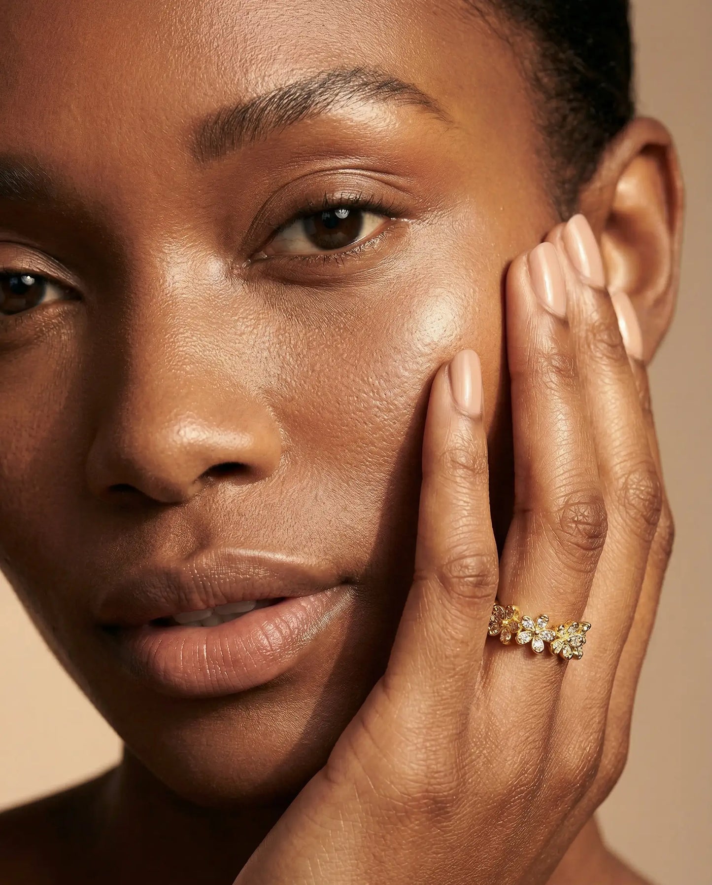Close-up of a person wearing a gold ring on a beige background