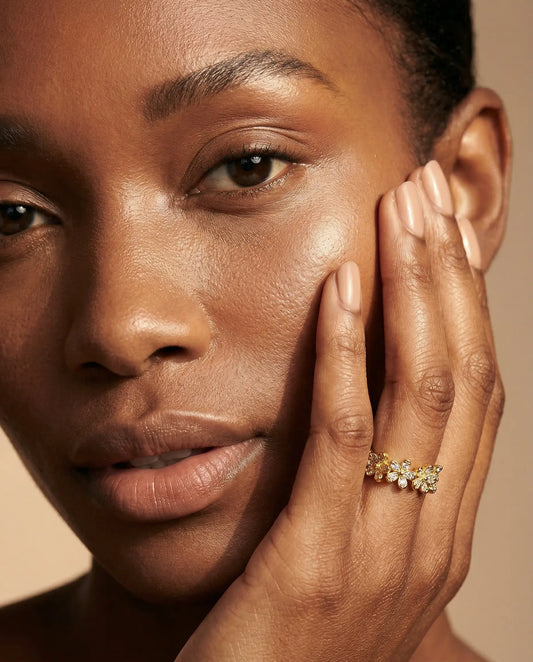 Close-up of a person wearing a gold ring on a beige background