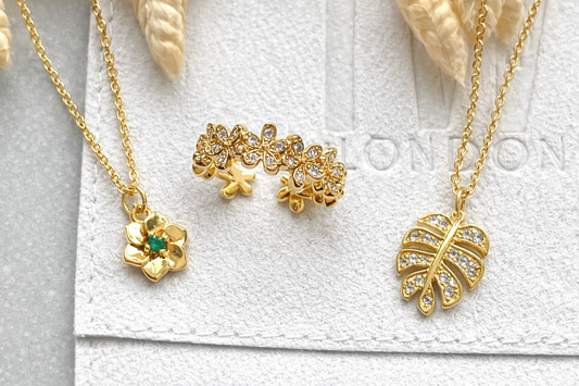 Gold jewelry set with floral and leaf designs on a white background