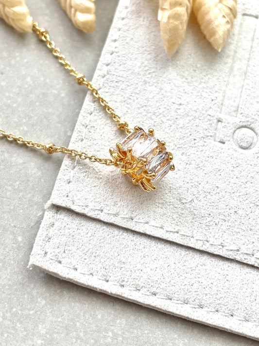 An 18k gold plated cubic zirconia polo necklace with a chain and a clasp, displayed on a textured background.