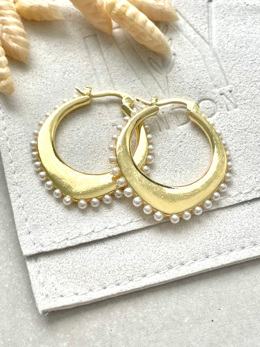 A pair of gold-plated pearl hoop earrings with exquisite faux pearls, displayed on a white surface.