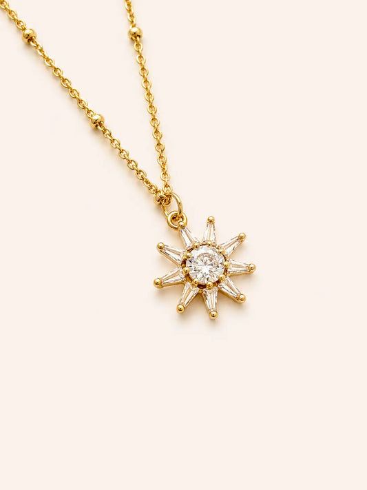 Gold necklace with a star-shaped pendant on a light beige background