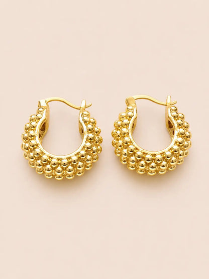 Gold hoop earrings with bead detailing on a beige background