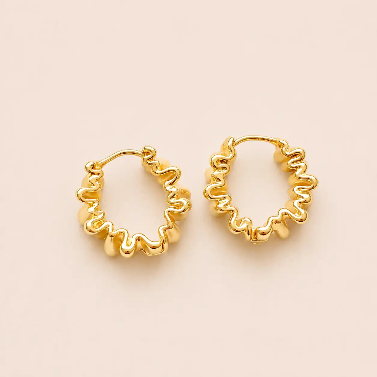 Gold hoop earrings on a beige background