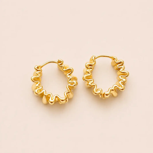 Gold hoop earrings on a beige background