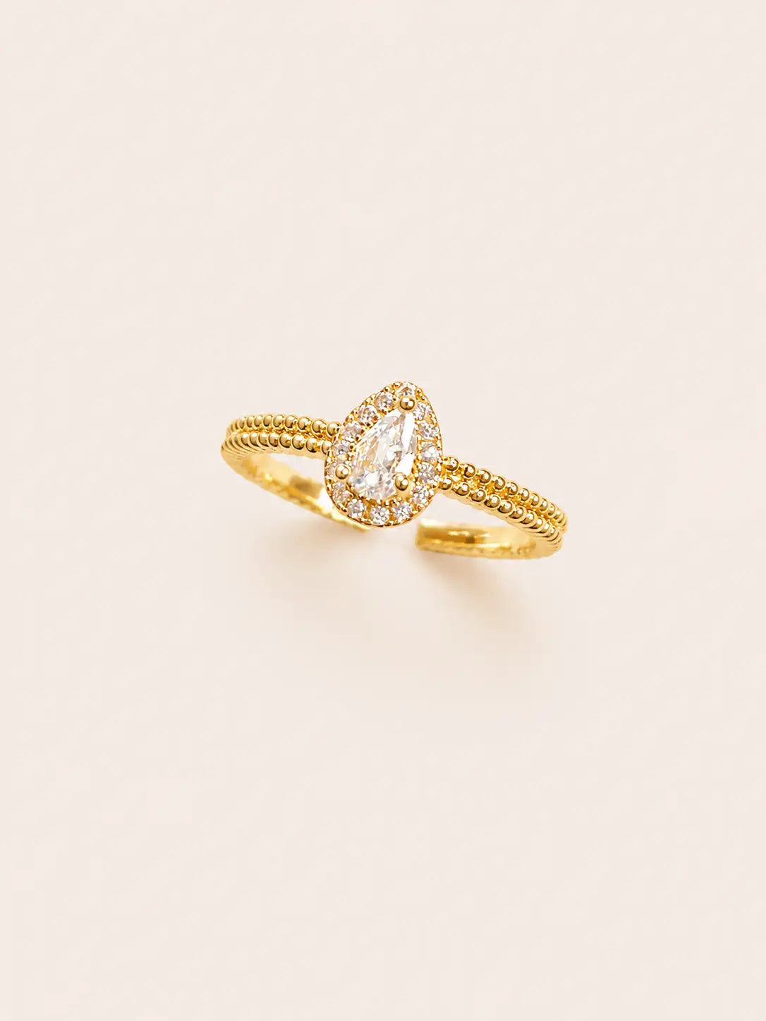 Gold ring with a diamond on a light beige background