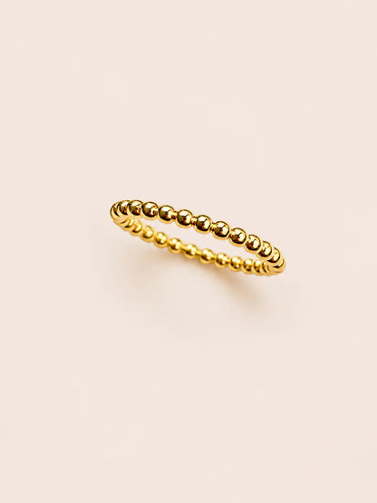 Gold beaded ring on a beige background